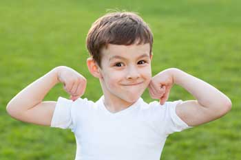 Kind grinnst in die Kamera und spannt die Muskeln an